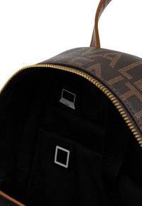 Bruine leren rugzak met een gouden rits, met een binnenzak en een laptopcompartiment. Het interieur is zwart met minimalistische hardware-accenten.