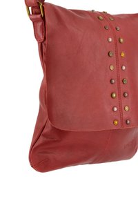 Rote Leder Schultertasche mit Klappenverschluss, die dekorative Metallnieten in verschiedenen Farben und Formen entlang der Mitte aufweist. Glatte Textur.