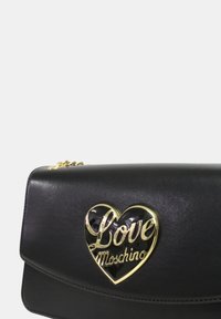 Borsa a tracolla in pelle nera con design a pattina. Presenta un logo a forma di cuore in tono oro decorato con "Love Moschino" in una finitura lucida.
