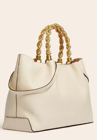 Sac à main en cuir crème avec une forme structurée, doté de poignées tressées de couleur dorée et d'une bordure noire le long des contours.