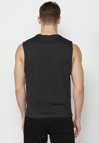 Svart ärmlös t-shirt i bomull. Har rundad halsringning och en avslappnad passform. Bakstycket är enkelt med en jämn textur.