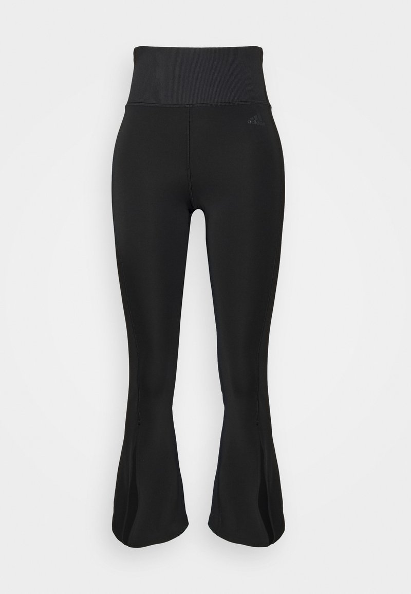 Leggings noirs évasés taille haute avec une ceinture côtelée et un discret logo Adidas sur la cuisse supérieure, présentés sur un fond blanc.