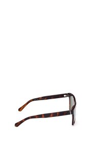 Lunettes de soleil écaille de tortue avec des verres carrés, monture épaisse et nom de la marque gravé sur les branches. Fini brillant, charnières robustes.