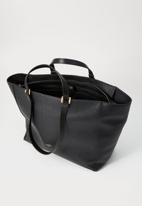 Sac fourre-tout en cuir noir avec finition texturée, doubles poignées, accents en métal doré, intérieur spacieux et design minimaliste.