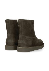 Botas de ante marrón oscuro hasta el tobillo con suela de goma plana, que cuentan con una cremallera lateral y un sencillo bordado en los bordes.