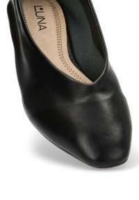 Zapato negro de cuero sin cordones con punta redondeada, textura suave y plantilla de color beige claro con costuras decorativas a lo largo de los bordes.