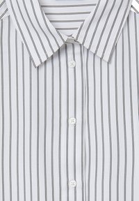 Camicia bianca con bottoni, caratterizzata da sottili righe verticali nere, colletto appuntito e cinque bottoni bianchi sul davanti. Tessuto dalla texture liscia.