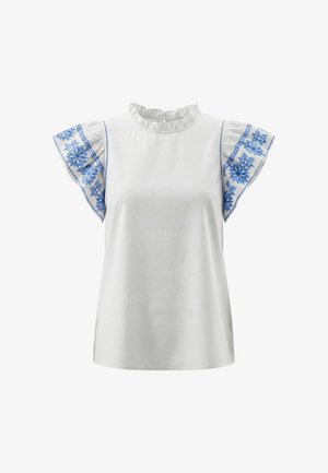 Hvid bluse med flæset krave og flagrende ærmer med blå blomsterbroderi på ensfarvet baggrund.