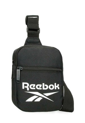 Bolso bandolera negro de Reebok con bolsillo frontal con cremallera, correa ajustable y logo blanco de Reebok en el frente.