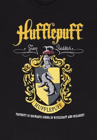 Sorte t-shirt med et gult Hufflepuff-våbenskjold, der viser et grævling, Quidditch-tekst og detaljer i hvid og guld.