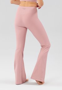 Leggings rosa a coste svasate con vita alta e dettagli cuciti, realizzati in materiale elasticizzato per comfort e flessibilità.