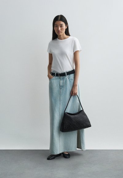 Denim-maksihame vaaleansinisena, yhdistettynä yksinkertaiseen valkoiseen t-paitaan. Varusteena musta kudottu käsilaukku ja mustat tasapohjaiset kengät.