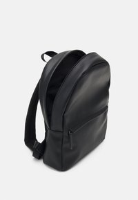 Zaino nero realizzato in materiale sintetico liscio, con parte superiore arrotondata, tasca frontale con zip e spallacci imbottiti e regolabili.