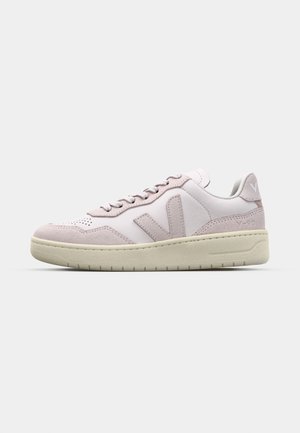 Rosa og hvite sneakers med glatte lær- og semskedelementer, runde snørebånd og en teksturert gummisåle med lav profil.