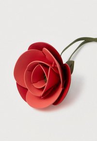 Piros bőr virág réteges szirmokkal, zöld szár és levél. Sima textúrájú és pontosan vágott formákkal rendelkezik.