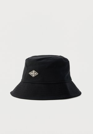 Sombrero tipo bucket negro con ala ancha y pequeño logo metálico en forma de diamante con la palabra "REPLAY" en el frente.