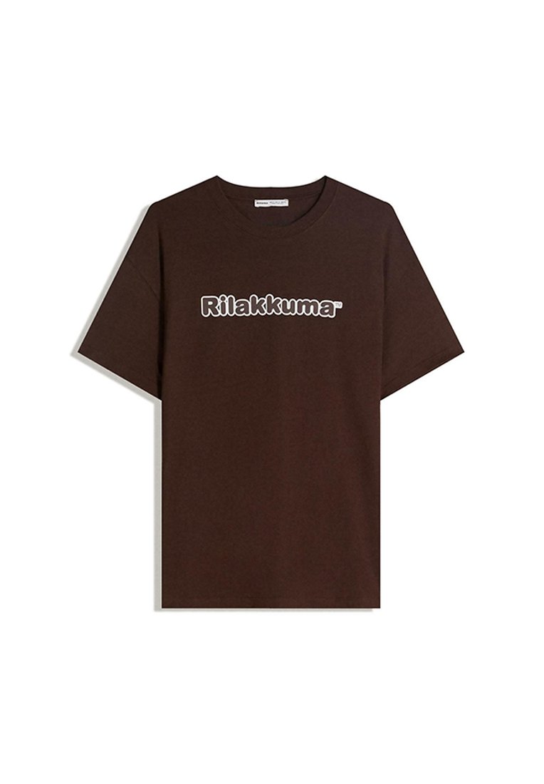 Brun bomulds t-shirt med rund hals og korte ærmer. Påskrevet tekst i hvid læser "Rilakkuma." Glat overflade, afslappet pasform.