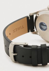 Bracelet de montre en cuir noir avec boucle en argent Timex, montrant l'intérieur du bracelet embossé avec le nom de la marque Timex.