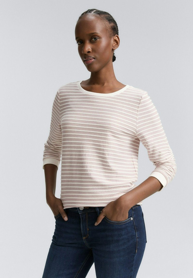Ljust rosa randig långärmad tröja med rund halsringning och vita manschetter, kombinerad med mörkblå jeans. Mjuk textur, avslappnad passform.