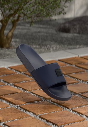 Sandale à enfiler bleu marine avec une sangle supérieure texturée et un accent logo noir. Dotée d'une semelle intérieure rembourrée et d'une semelle extérieure en caoutchouc.