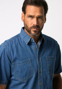 Korte mouwen denim overhemd in medium blauw met knoopsluiting, twee voorkantzakken en een kraag met stikseldetails.