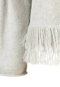 Weiches, hellgraues gewebtes Material mit einem Fransenrand, das eine detaillierte Textur und lose Quasten auf einer Seite zeigt.