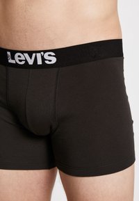 Schwarze Baumwoll-Boxershorts mit breitem elastischem Bund mit "Levi's"-Logo in Weiß, enger Passform und glatter Textur.