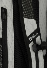 Zaino grigio e nero con pannelli in rete, tessuto a motivo diamante, una cerniera e un'etichetta con logo raffigurante un'impronta di zampa.