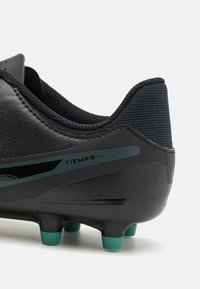Svarte fotballsko med skinnoverdel, ribbet krage, teal-detaljer og koniske knotter for grep. Bruksfokusert design.