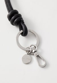 Llaveros de cuero negro con una textura suave, que cuenta con un anillo de metal plateado, un broche y una etiqueta redonda grabada con "Marc O'Polo."