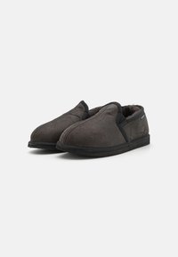 Chaussons en polaire grise avec une texture lisse, un design à bout rond et des finitions noires. Doublure douce et semelle plate et flexible.