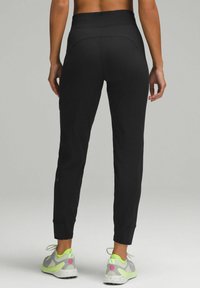 Svarta träningbyxor med en figurnära design, avsmalnande anklar och hög midja. Materialet verkar slätt och elastiskt, vilket gör dem lämpliga för aktivt bruk.