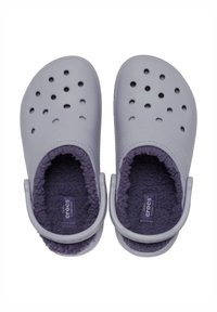 Helle graue Crocs Clogs mit Belüftungslöchern und einem weichen, lila Fleecefutter. Sie verfügen über einen Rückstraps für einen sicheren Sitz.
