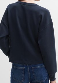 Mörkblå sweatshirt med relaxed fit, sänkta axlar och rund halsringning. Mjukt tyg med slät yta och minimala sömdetaljer.