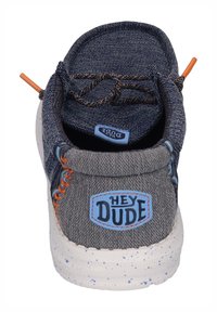 Le scarpe casual da uomo presentano una tomaia in denim blu, dettagli di cucitura arancione, corpo in tela grigia e una suola bianca texturizzata con lentiggini blu.