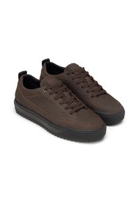 Un paio di sneakers basse di colore marrone scuro con suole in gomma nera, chiusura con lacci e dettagli cuciti su uno sfondo bianco.