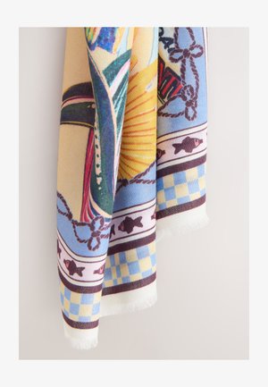 Huivi, jossa värikkäitä meriteemaisia kuvioita, kuten kaloja, köysiä, auringonsäteitä ja sininen ja keltainen ruudullinen reuna, roikkuen vaaleaa taustaa vasten.