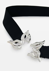 Cinturón elástico negro con doble hebilla de metal plateado brillante en un diseño fluido y abstracto que recuerda a figuras.