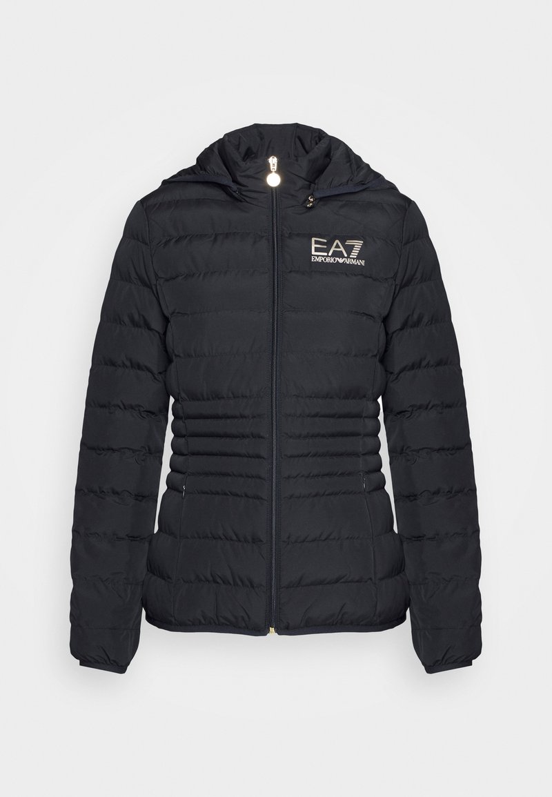 Chaqueta tipo abrigo negra con cremallera frontal, diseño acolchado horizontal, capucha y logo de EA7 en dorado. Presenta dos bolsillos laterales y puños elásticos.