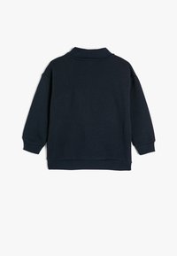 Sudadera azul marino con un cuello y puños acanalados, presenta un corte relajado y una textura suave. Sin patrones visibles ni detalles metálicos.