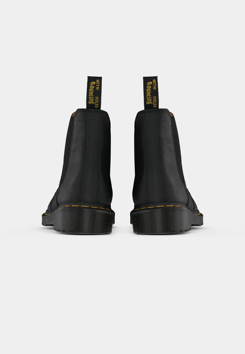 Pair of black leather ankle boots with yellow stitching, textured soles, and black pull tabs with yellow text "WITH Bouncing SOLES" centered on white background.