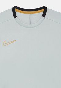 Šviesiai pilkas sportinis marškinėliai su apvaliu iškirpimu, juodais ir geltonais akcentais bei išsiuvinėtu Nike logotipu kontrastinga oranžine spalva.