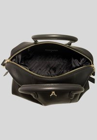 Borsa a tracolla in pelle nera con hardware dorato, chiusura a zip e doppi manici superiori. L'interno presenta una fodera in tessuto con motivo e dettagli del logo.