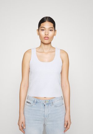 Απαλή γκρι ριγέ αμάνικη μπλούζα με τετράγωνη λαιμόκοψη και φαρδιές τιράντες. Συνδυάζεται με ανοιχτό μπλε τζιν παντελόνι.