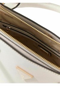 Witte gestructureerde handtas met gouden hardware, ritssluitingen en een logodetail aan de binnenzijde. Gestructureerd buitenmateriaal met zwarte accenten.