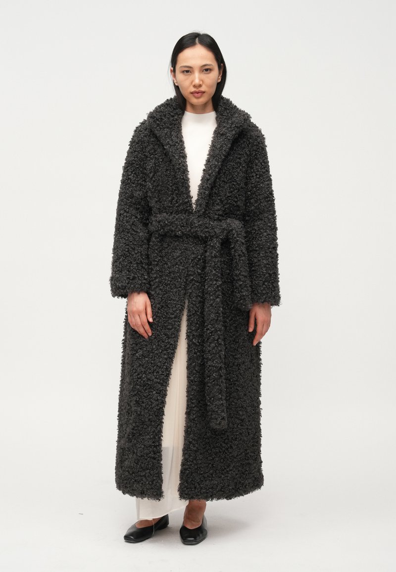 Plišani, tamnosivi ogrtač s širokim ovratnikom i remenom. Dugi rukavi, otvoreni sprijeda i mekani, teksturirani materijal. Nosi se preko svijetle haljine.