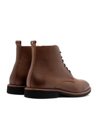 Brązowe skórzane botki za kostkę z teksturowanym wykończeniem, sznurowane z przodu, z płaską czarną podeszwą. Posiadają pętelkę na pięcie ułatwiającą zakładanie.