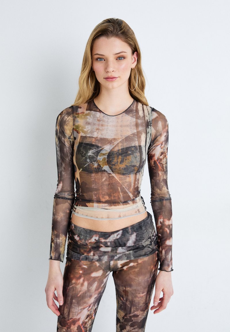 Langarmtop en bijpassende leggings van een sheer, textuurstof met een abstract aards patroon in bruin- en grijstinten.