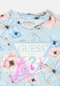 Φωτεινό γαλάζιο οργανικό βαμβακερό μπλουζάκι με floral μοτίβα σε ροζ και μπλε, με κεντρικό τριγωνικό λογότυπο και ροζ γραφικό κείμενο "Love".