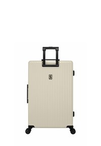 Harde koffer in lichtbeige met verticale ribbelstructuur, zwarte handgreep en wielen voor gemakkelijk transport. Bevat een logo aan de voorkant.